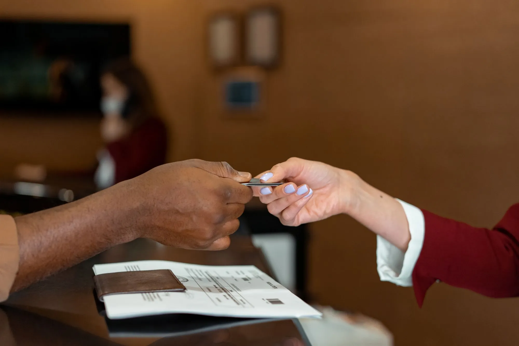 An airline agent smiling as she hands a passenger their documents.