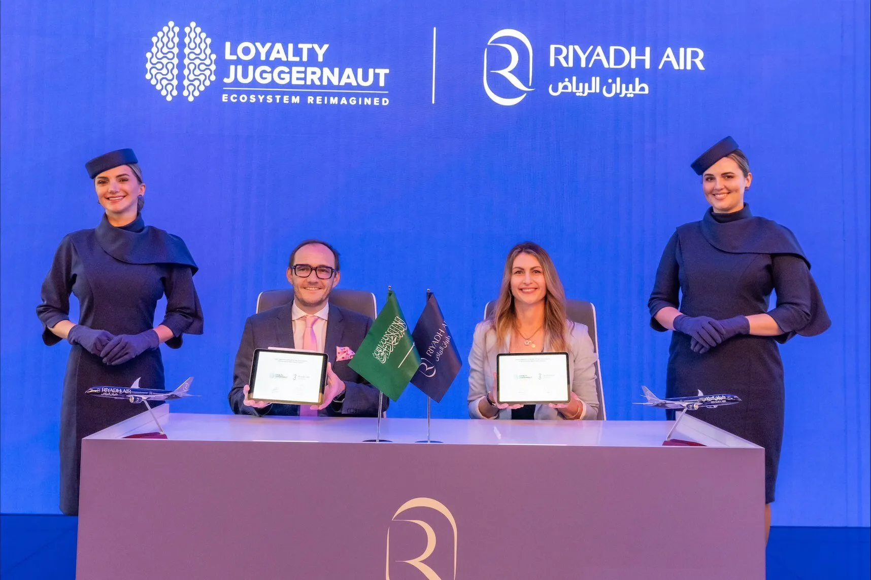 Riyadh Air and Loyalty Juggernaut sign their partnership, flanked by Riyadh Air cabin crew.
